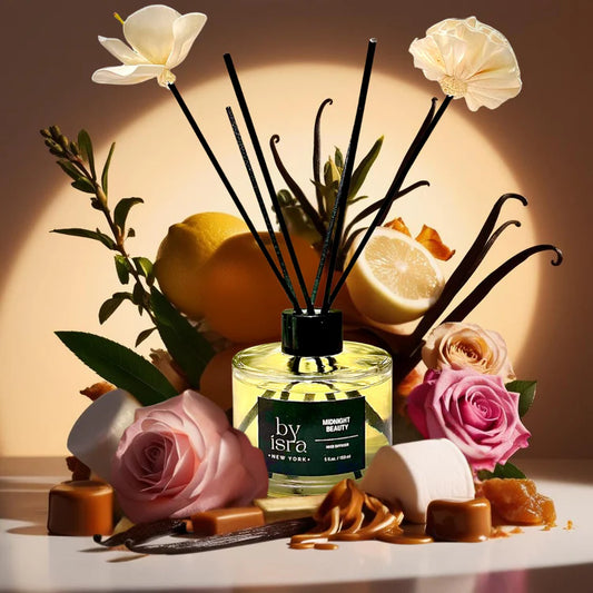 A diffuser with flowers, lemons, and roses on a wooden surface with a warm glow.