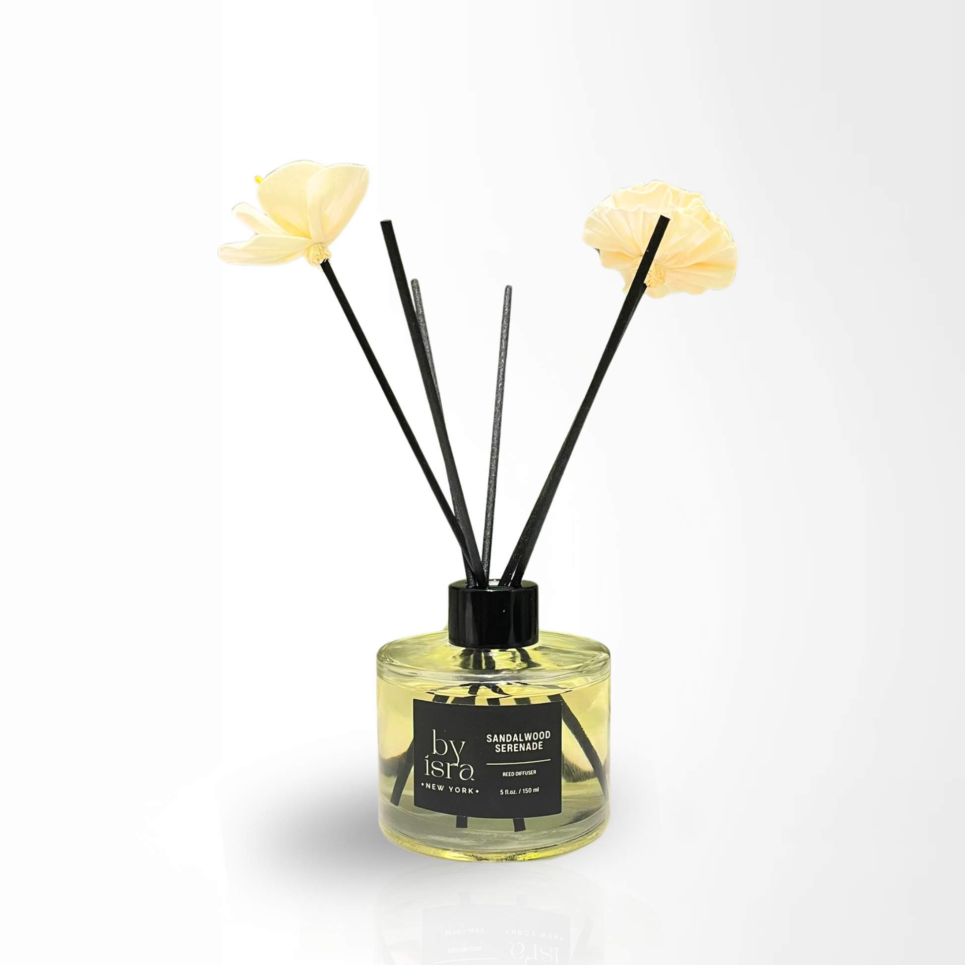 Reed diffuser with black sticks and yellow flowers in a clear bottle on a white background